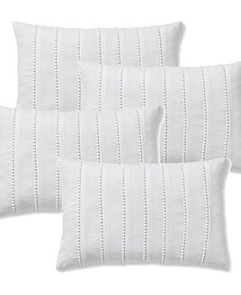 Small white, oblong bolster cushion covers with rows of small pom pom details.