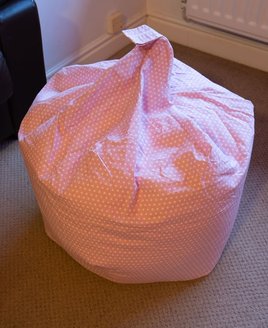 Pink bean bag with a white polka dot pattern
